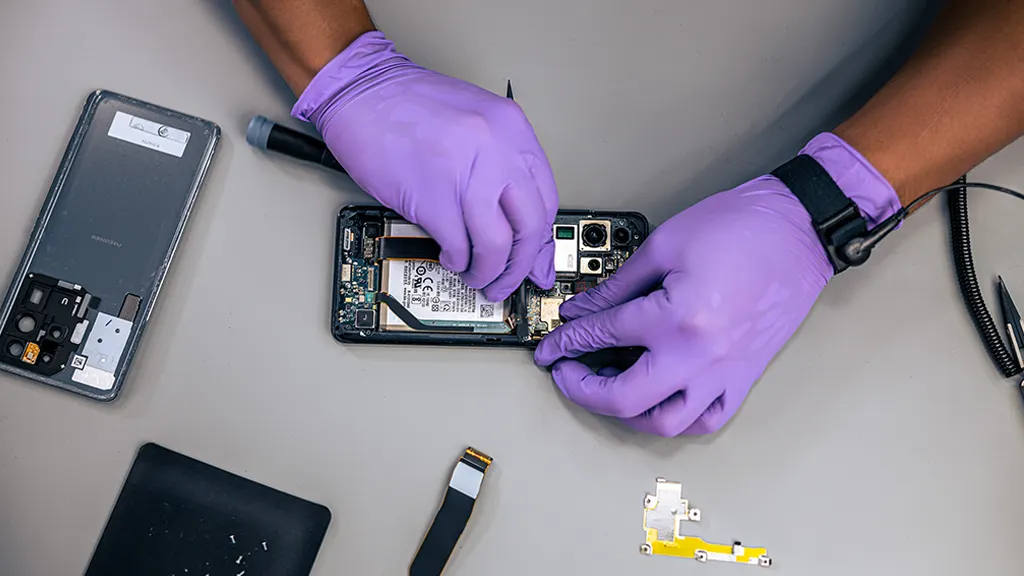 Technician repairing a Samsung Galaxy phone at the ASM Wireless bench